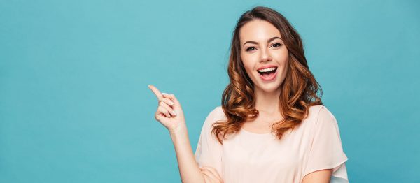 young woman smiling and pointing behind her