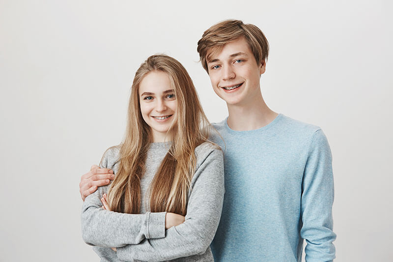 teen boy and girl smiling with braces