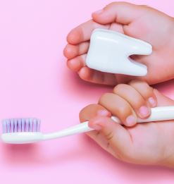 young child holding a toothbrush and dental floss