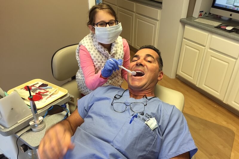 Dr. DeQuattro getting his dental checkup by a child patient